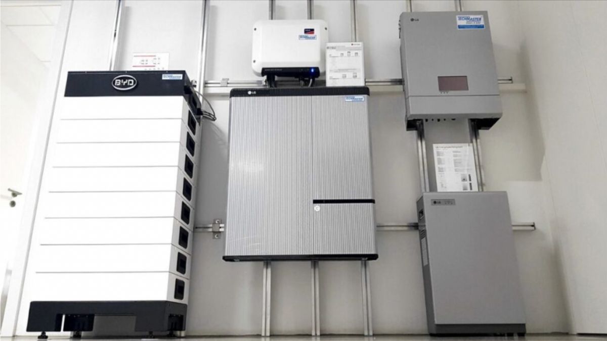 Een hele grote witte BYD thuisbatterij hangt aan een muur samen met andere batterijen