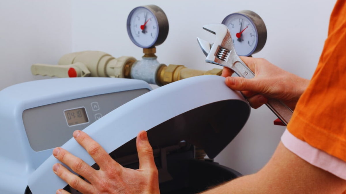 Installateur opent de behuizing van een elektronische waterontharder voor installatie of onderhoud