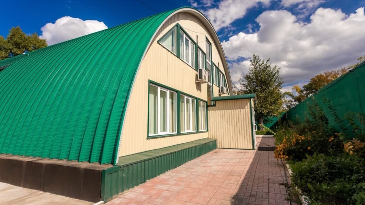 Een opvallend, felgroen gebogen dak. Het dak reikt niet alleen over de bovenkant van het gebouw, maar ook over de zijkanten.