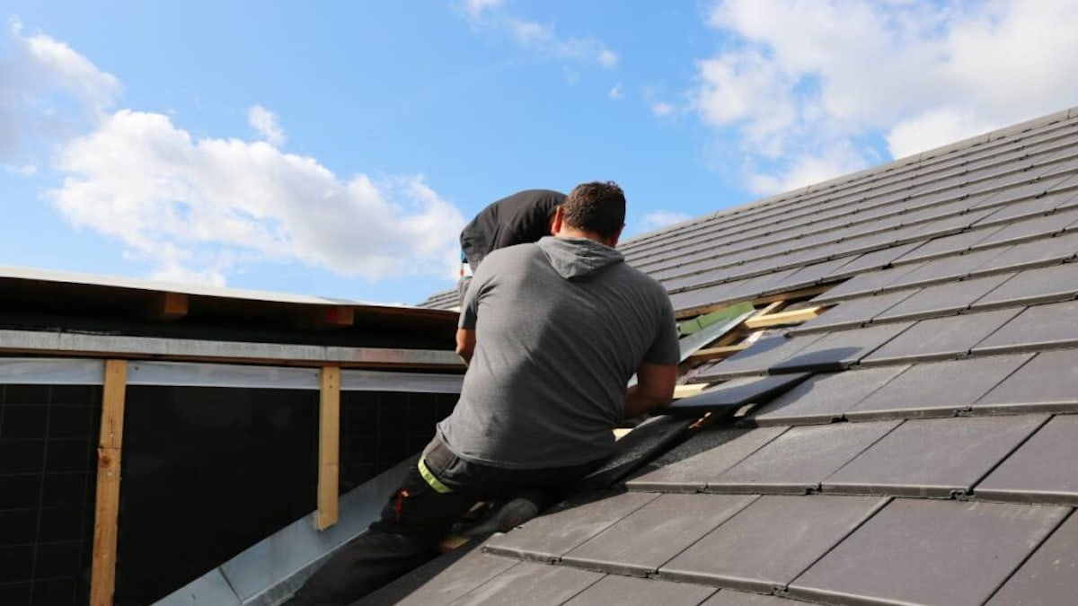 Dakwerkers plaatsen een prefab dakopbouw op het pannendak.
