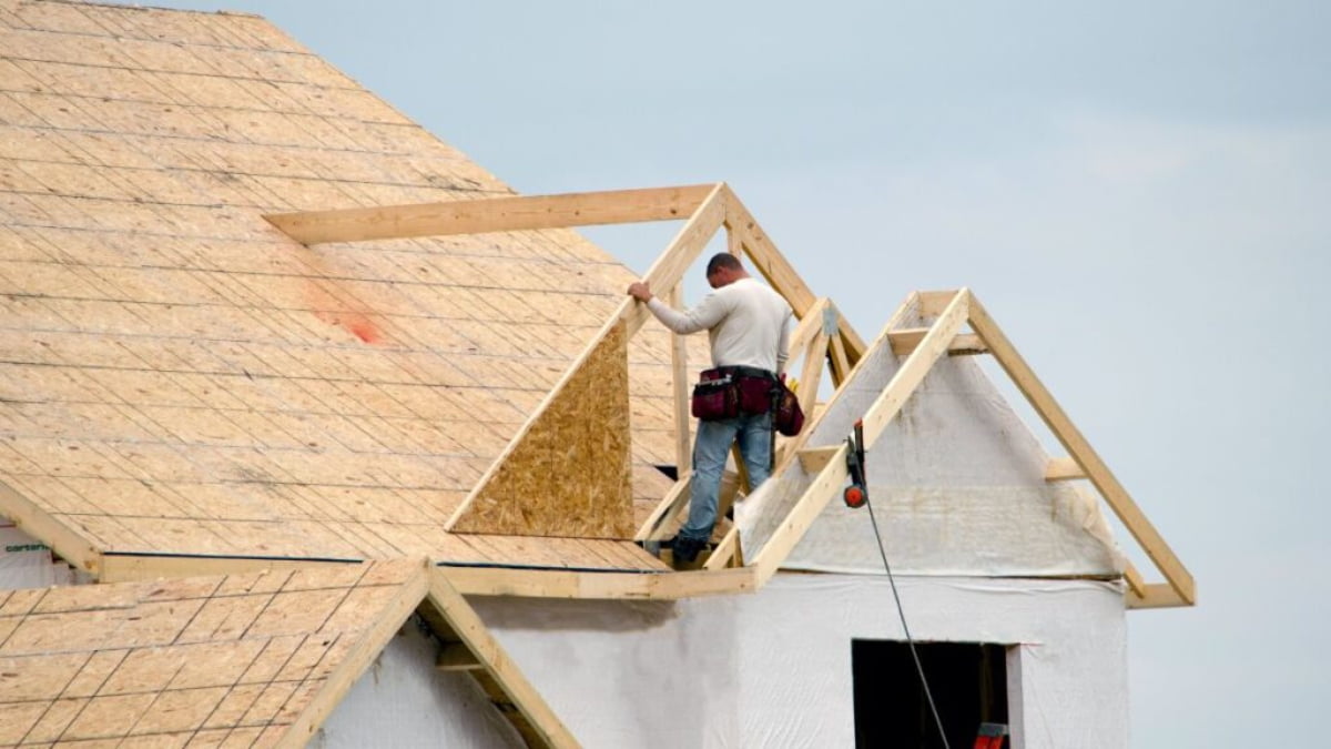 Een dakdekker controleert een houten dakconstructie.