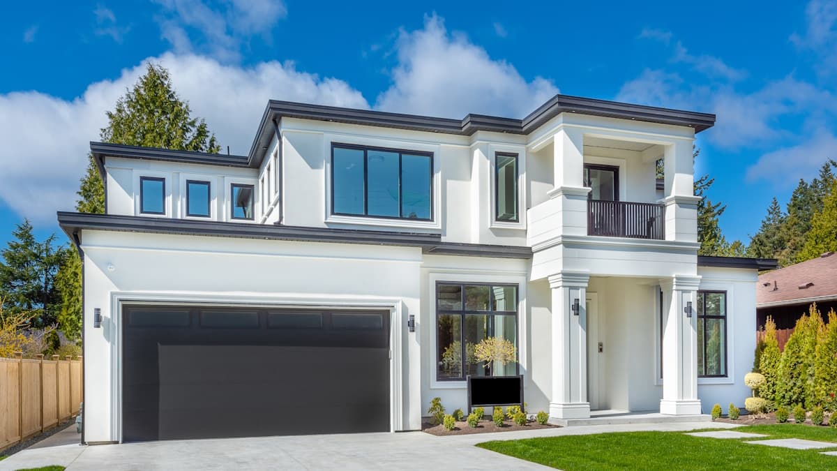 Een witte woning met een grijs plat dak. Op twee woonlagen is een dak geplaatst.